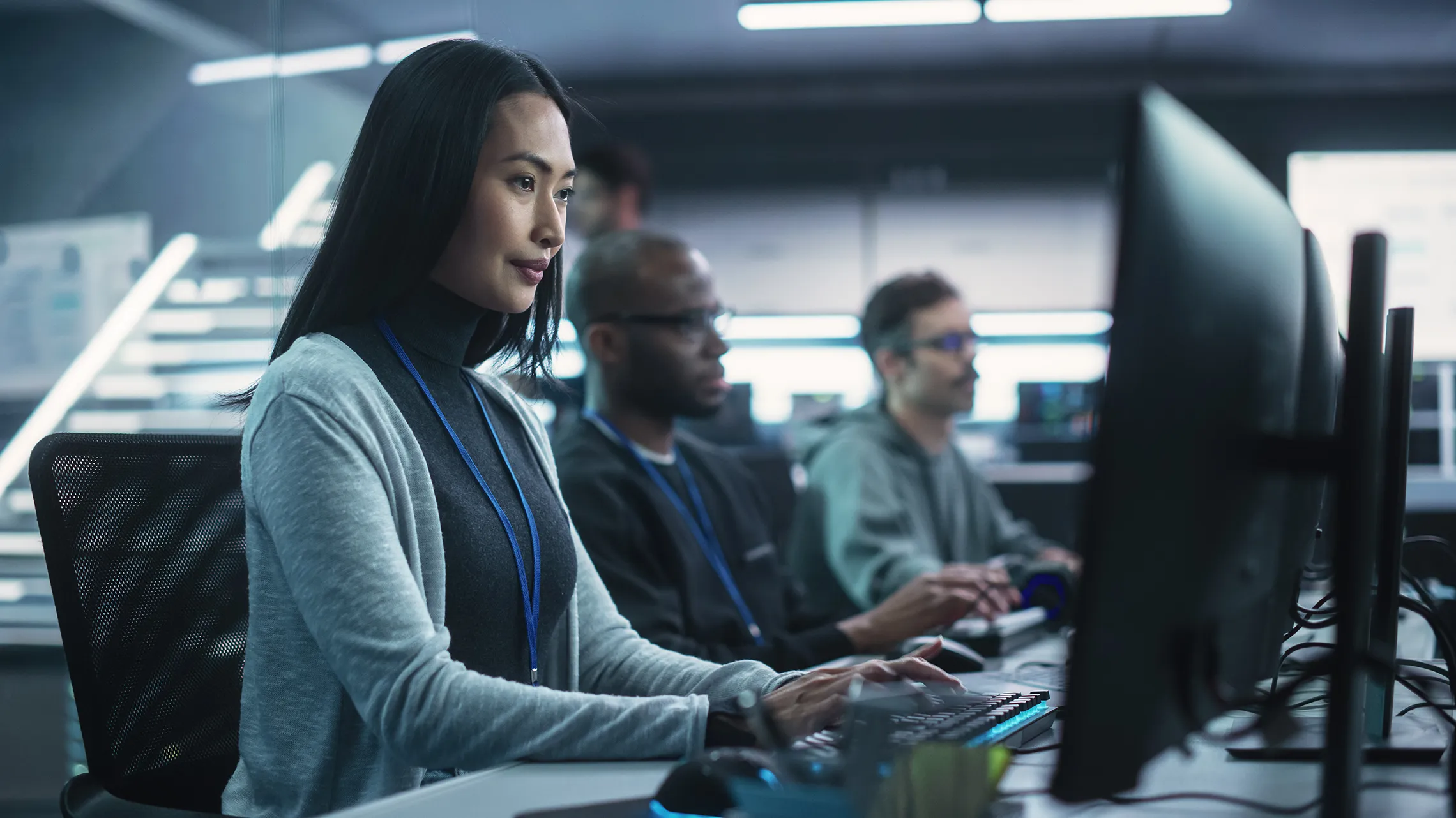 Team of IT specialists working on computers in a secure, high-tech office space.