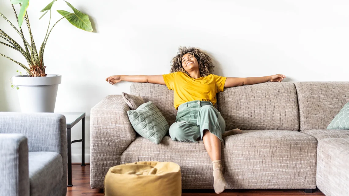 A woman enjoying a relaxed moment on her couch, symbolising balance and harmony.