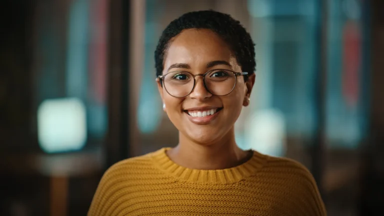 Smiling professional woman in a modern office environment, representing user-focused innovation.