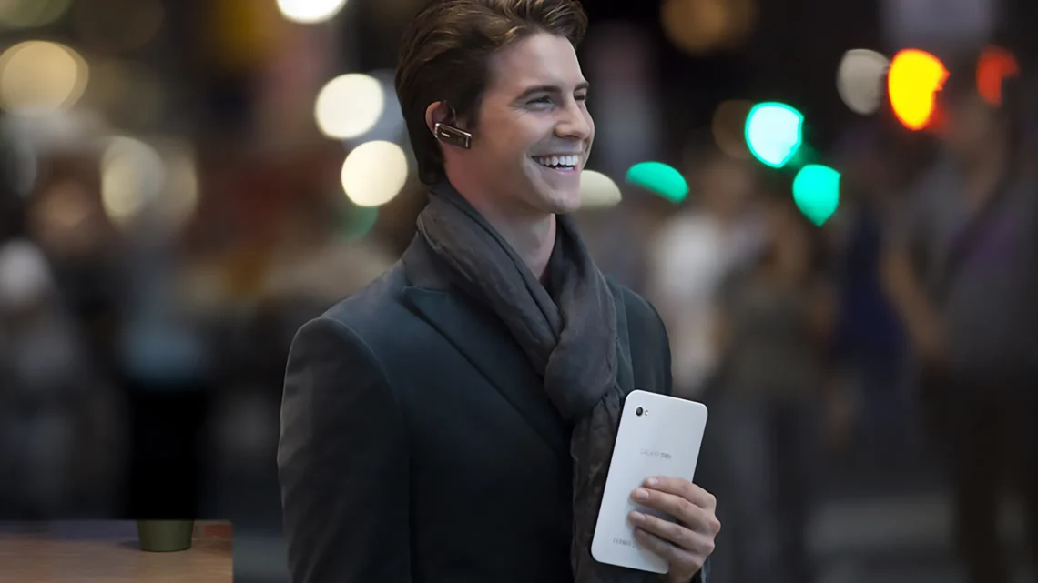 A man holding a Samsung Galaxy Tab in an urban setting, smiling while staying connected with modern technology.