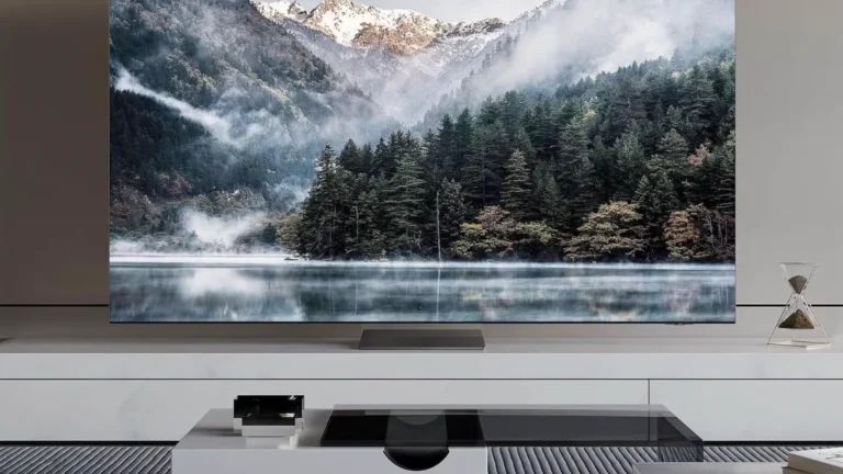 A Samsung Smart TV displaying a scenic view of mountains and a lake, placed in a modern living room.