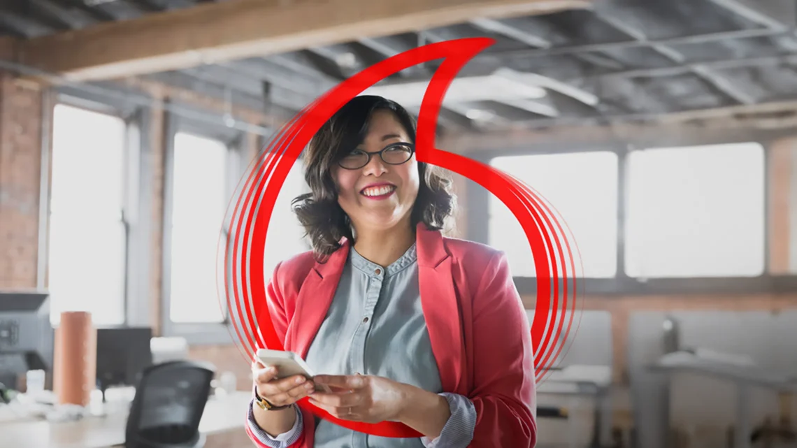 Business professional using a smartphone with Vodafone’s logo overlayed.